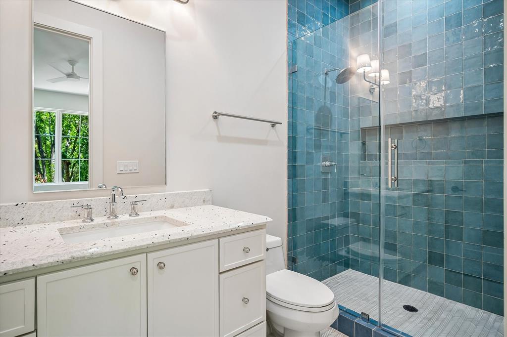 Bath, blue glazed tile shower, single vanity, frameless glass enclosure