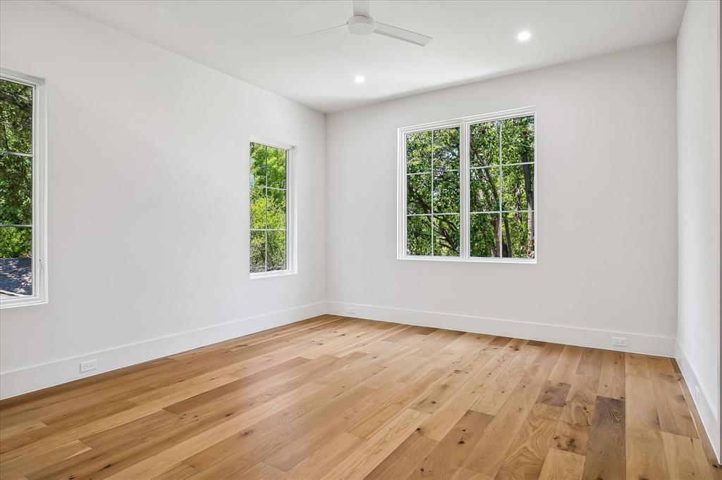 Secondary bedroom, hardwood floors, multi-window views, ceiling fan