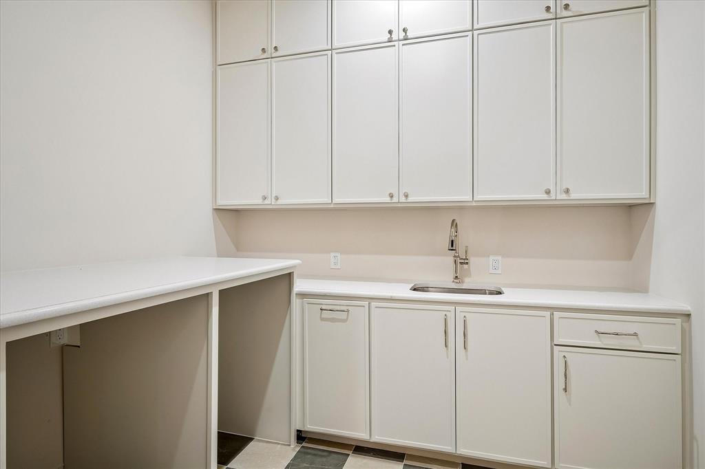 First-floor laundry, built-in cabinetry, utility sink, stone countertop