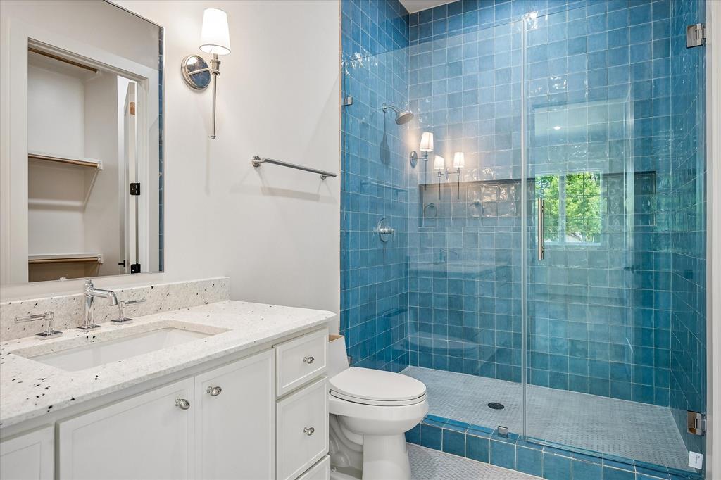 Bath, blue glazed tile shower, frameless glass enclosure, stone countertop, shower niche