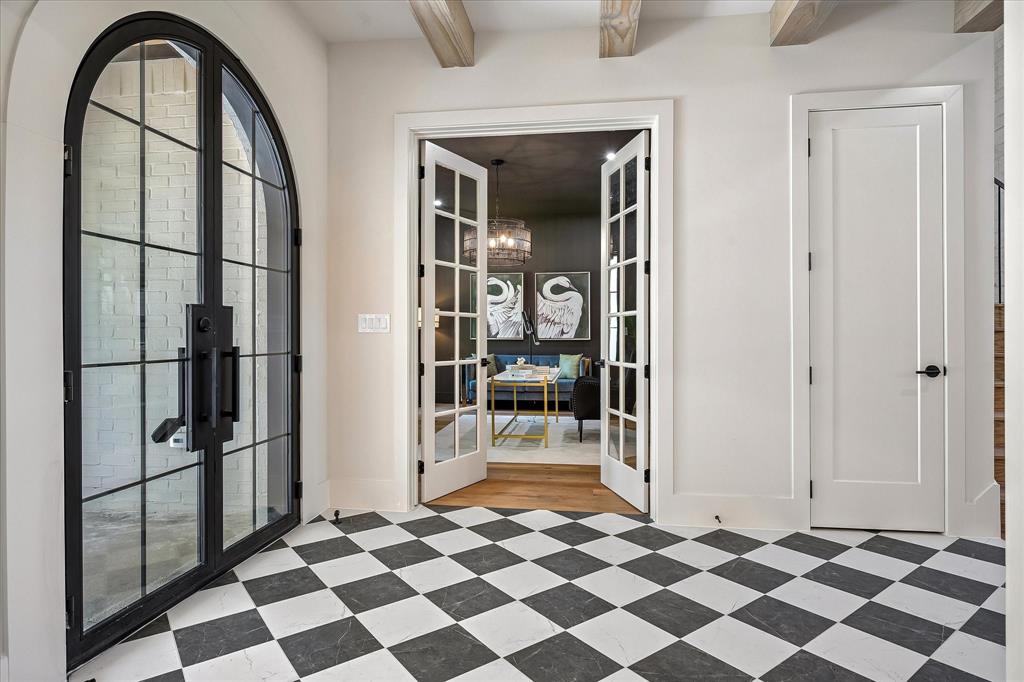 Arched iron and glass entry, checkered tile floor, French doors to study, exposed beam ceiling Arched iron and glass entry, checkered tile floor, French doors to study, exposed beam ceiling