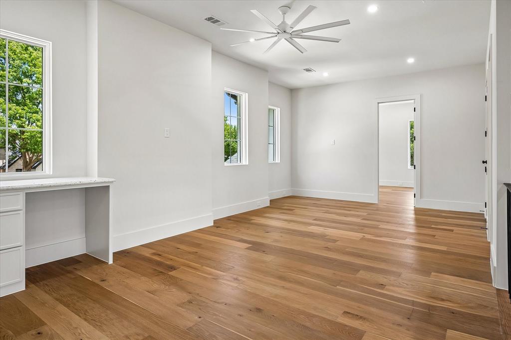 Secondary bedroom, hardwood floors, ceiling fan, built-in desk, multi-window views