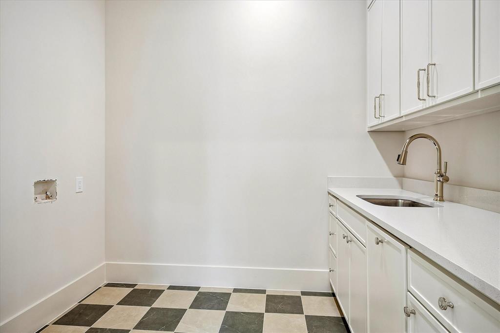 Second-floor laundry, built-in cabinetry, utility sink, stone countertop