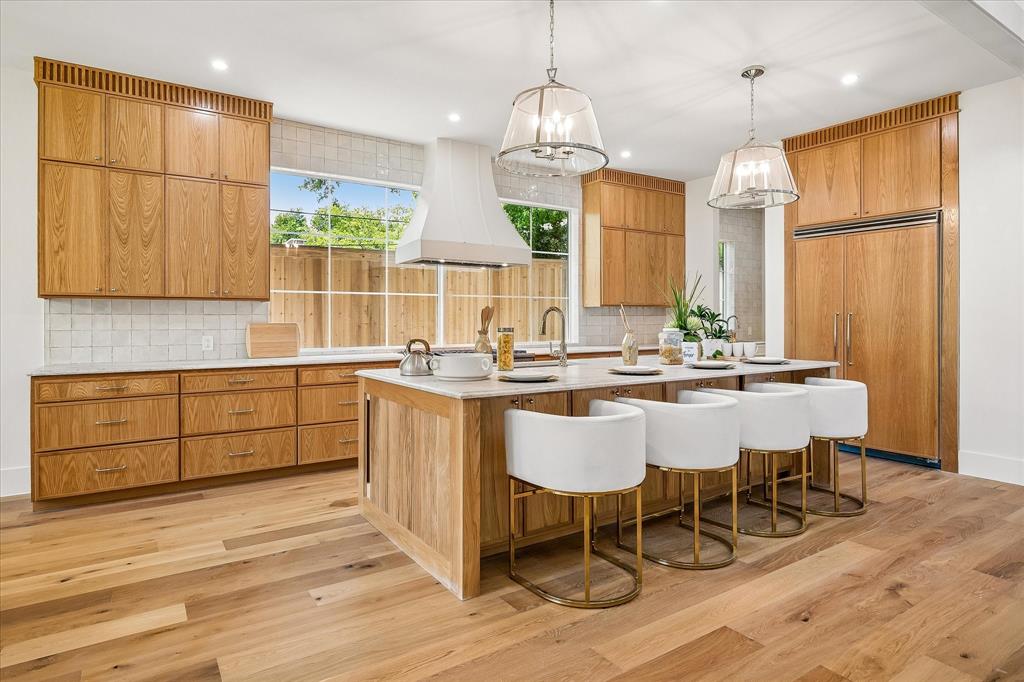 Custom oak cabinetry, Taj Mahal leathered quartzite island with bar seating, panel-ready refrigerator