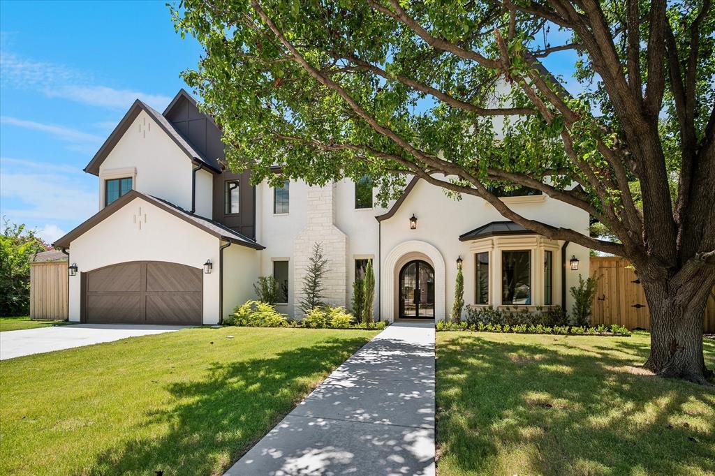Maison Manor Homes new construction, stucco and stone facade, arched iron entry, wood-panel garage door