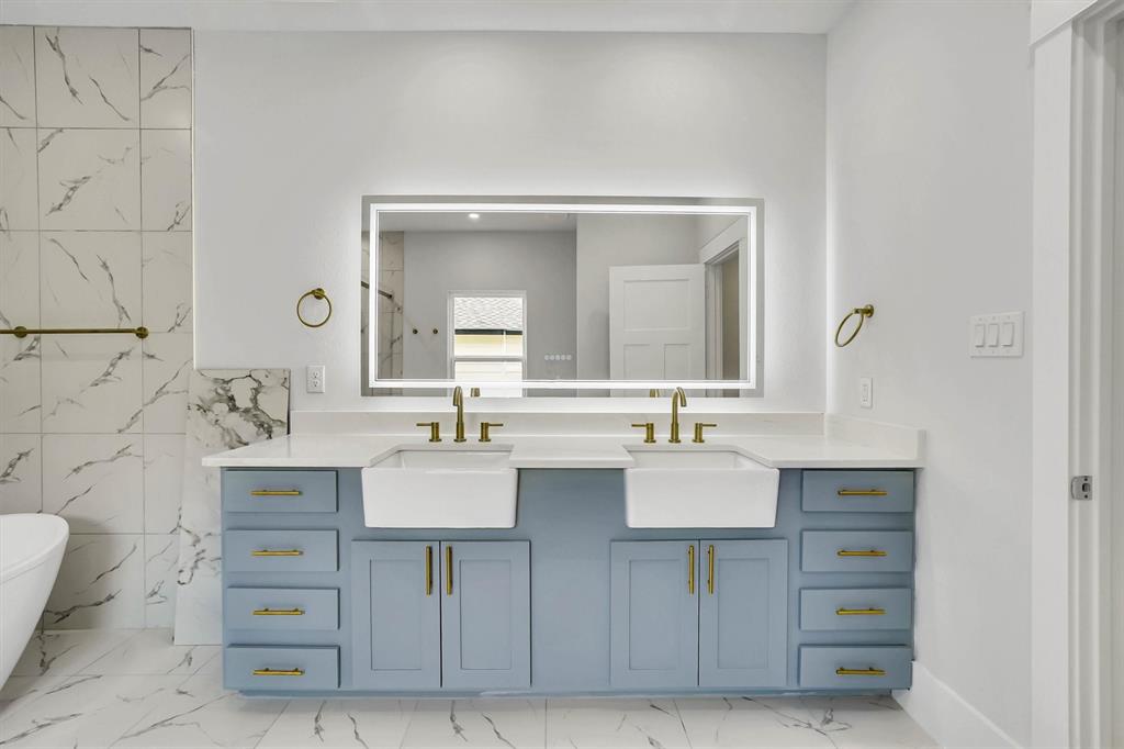 Double vanity with light gray-blue cabinetry and gold-tone hardware