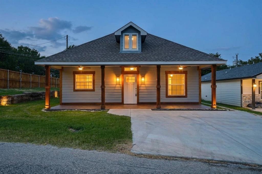 Exterior facade featuring horizontal siding, a covered front porch with timber posts, a gabled roofline with a dormer window, and a concrete driveway