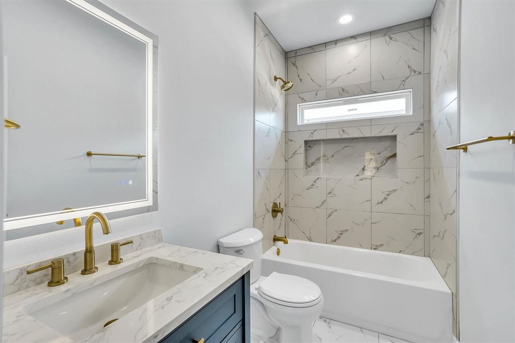 Bathroom featuring a white vanity with a marble-finish countertop, a single undermount sink, and brass-tone fixtures