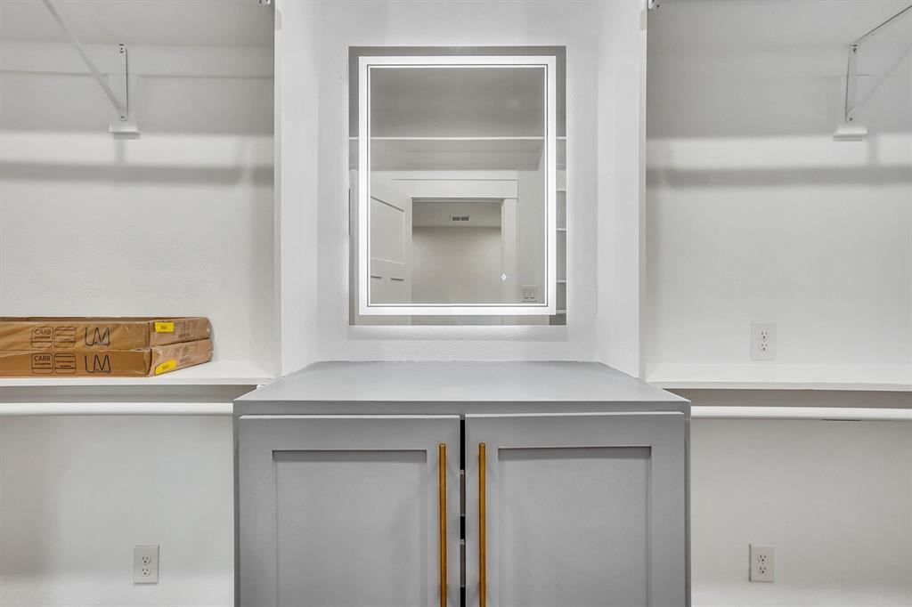 Built-in closet system featuring a central island with gray cabinetry and gold-tone hardware