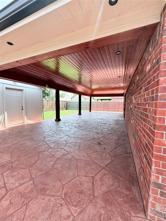 Expansive covered patio featuring stamped concrete flooring and a wood-finish ceiling with recessed lighting