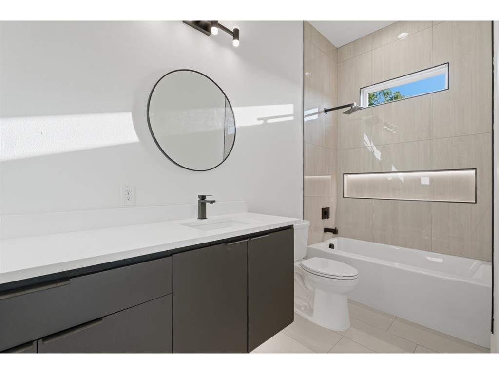 Contemporary bathroom featuring a dark gray floating vanity with a white countertop and a circular mirror