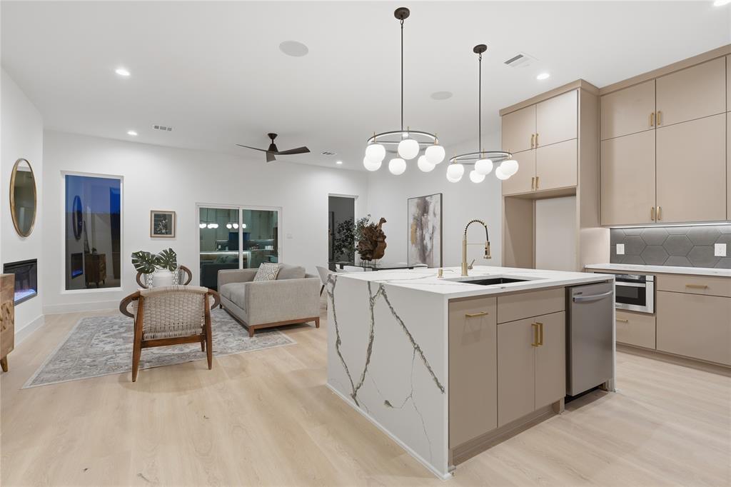 Open-concept living space featuring light wood-finish flooring, a modern kitchen island with integrated sink, and recessed lighting