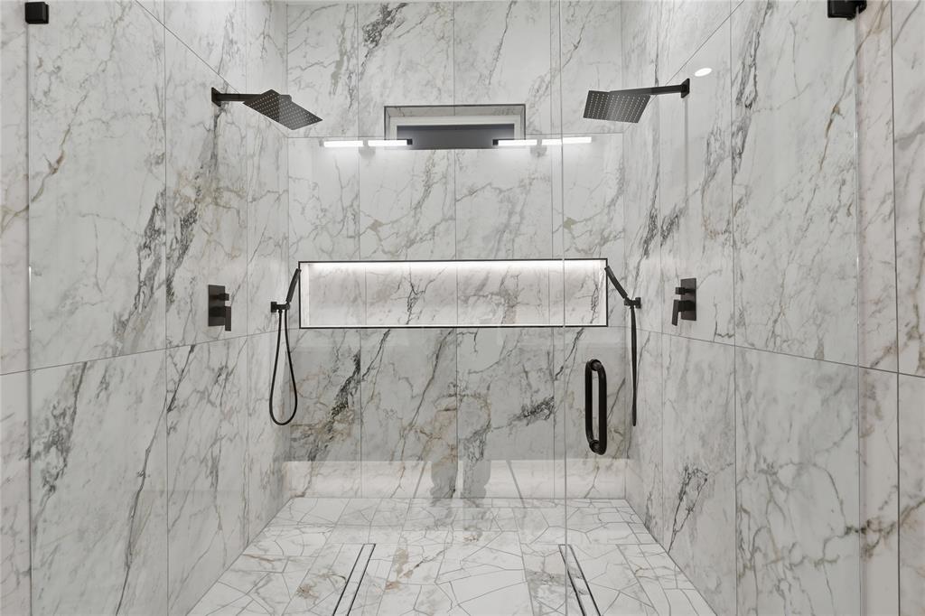 Spacious walk-in shower featuring marble-look wall and floor tiling