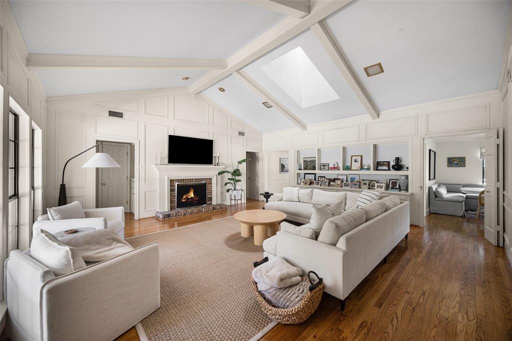 Spacious living area featuring a vaulted ceiling with exposed beams, skylight, and recessed lighting