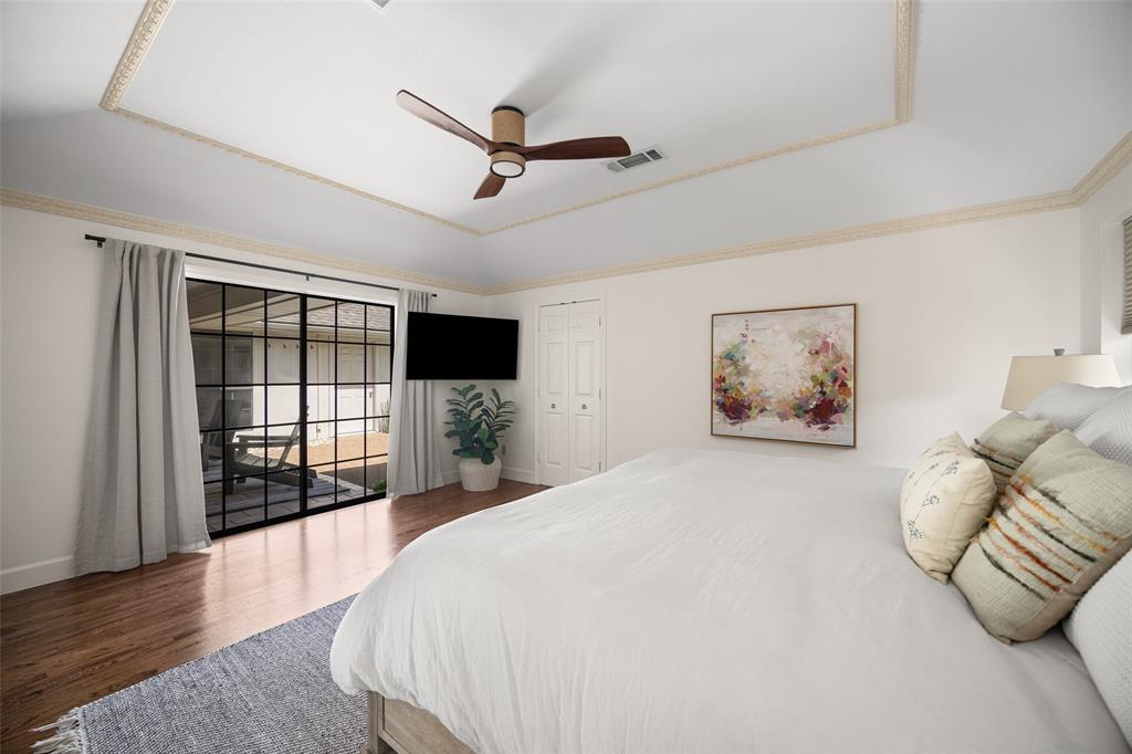 Tray ceiling with decorative molding, wood-finish flooring, and black-framed glass sliding doors leading to an outdoor space