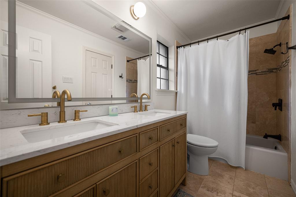 Bathroom featuring a double vanity with gold-tone fixtures, a white countertop, and integrated sinks