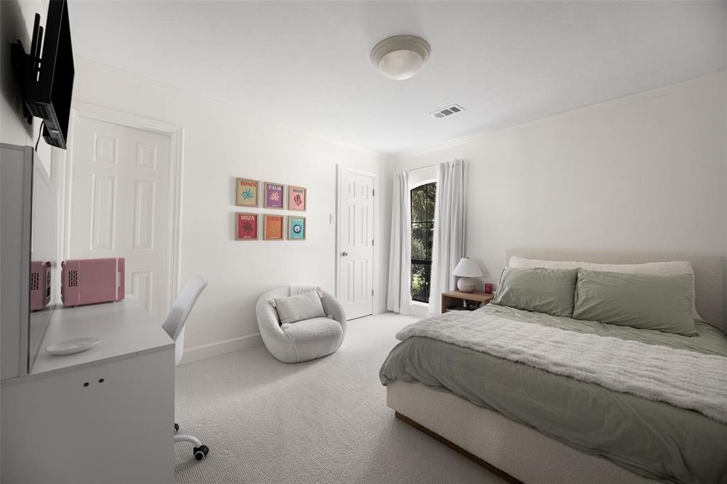 Spacious bedroom featuring light-colored carpeting, white painted walls, and a large window with white curtains