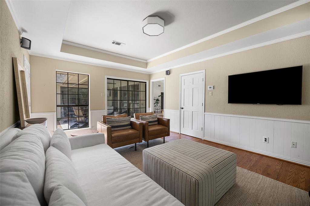 Living area featuring wood-finish flooring, white wainscoting, and a tray ceiling