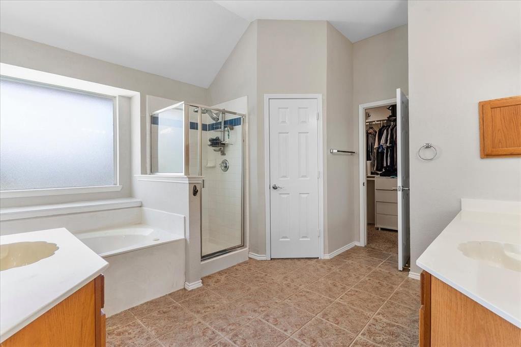 Bathroom featuring a separate shower enclosure with glass surround, a built-in soaking tub, and dual vanity areas with wood cabinetry