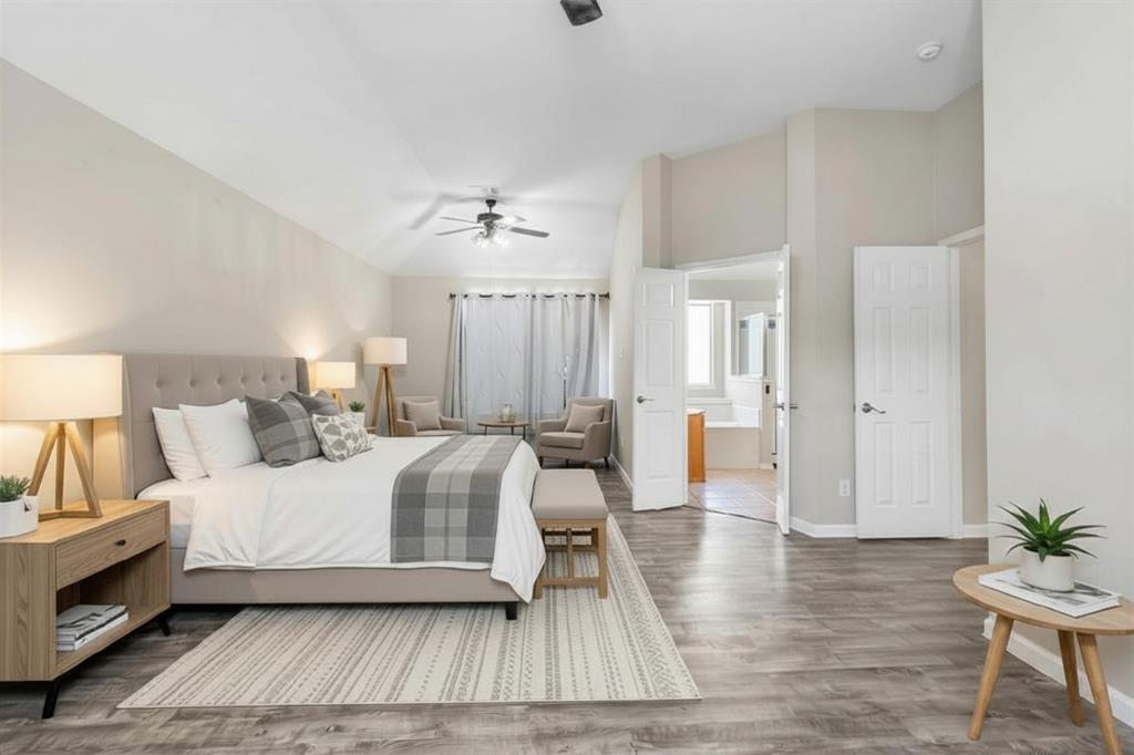Spacious bedroom featuring wood-finish flooring, a ceiling fan with integrated lighting, and a recessed sitting area