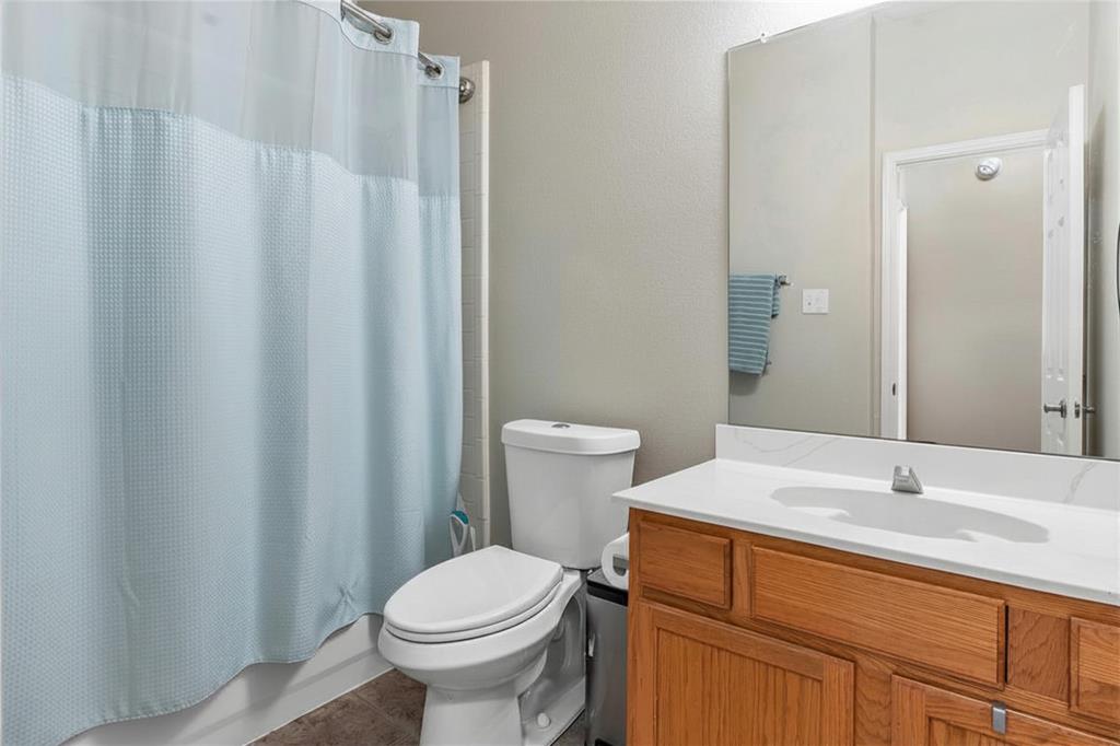 Spacious bathroom featuring a wood-finish vanity with dual-sink countertop, large framed mirror, and ample storage