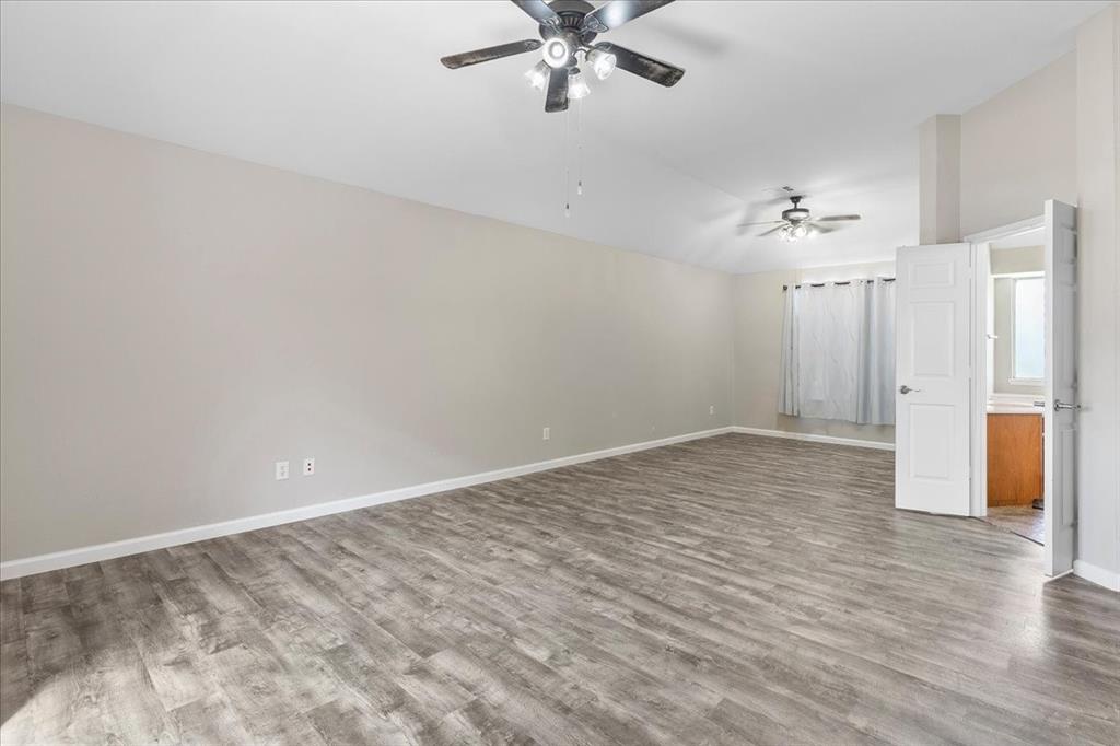 Spacious room featuring vaulted ceilings, wood-finish flooring, and multiple ceiling fans