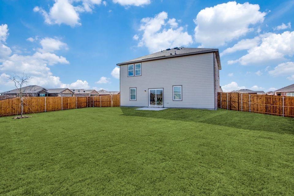 Expansive rear yard featuring a privacy fence, a concrete patio, and a two-story exterior with siding