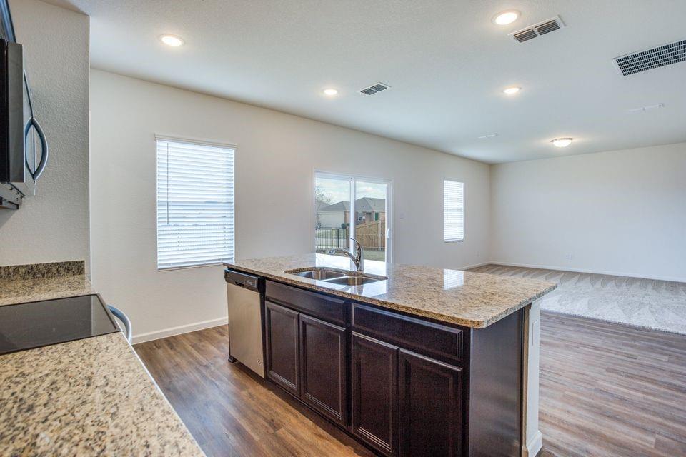 Kitchen island featuring a double-basin sink, stainless steel dishwasher, and granite countertop Kitchen island featuring a double-basin sink, stainless steel dishwasher, and granite countertop