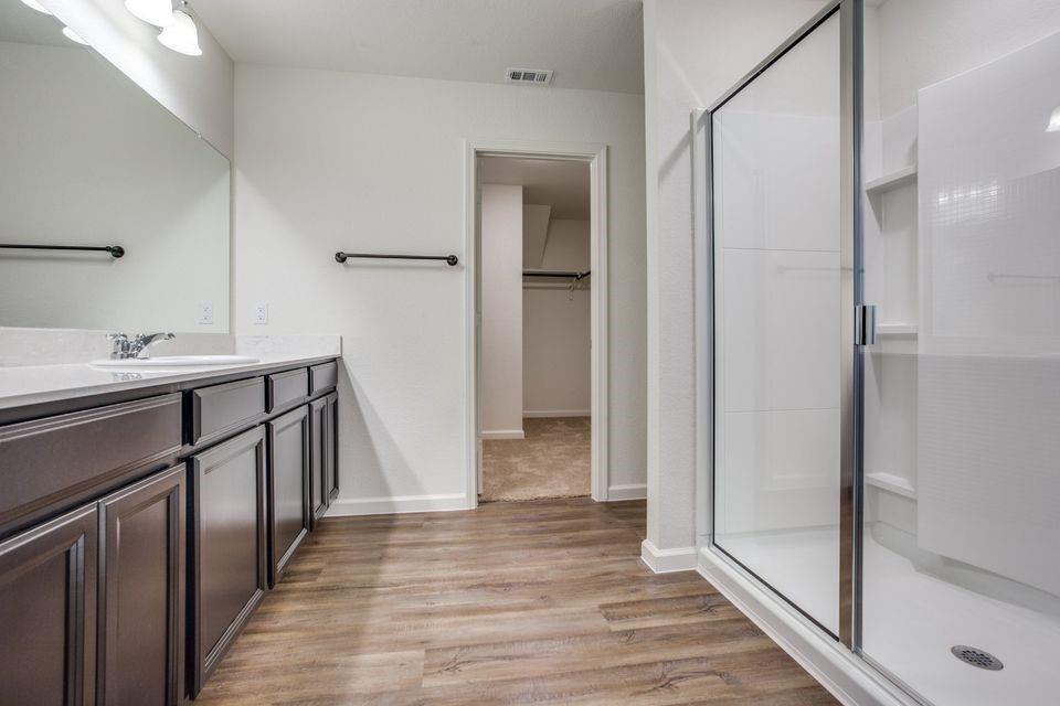 Bathroom featuring a wide vanity with dark cabinetry, a single basin sink, and a spacious mirror Bathroom featuring a wide vanity with dark cabinetry, a single basin sink, and a spacious mirror