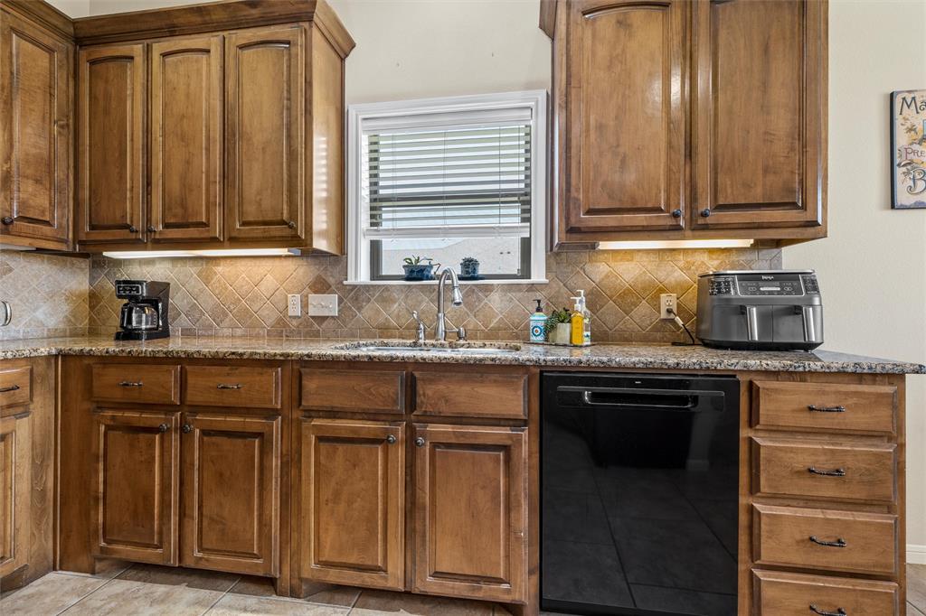 Kitchen featuring wood cabinetry, granite-style countertops, and a tiled backsplash