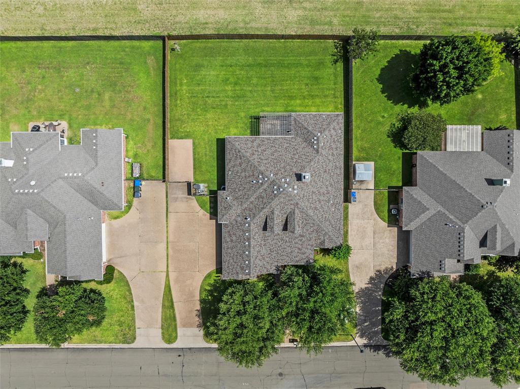 Expansive aerial view showcasing a residential property with a shingled roof and concrete driveway