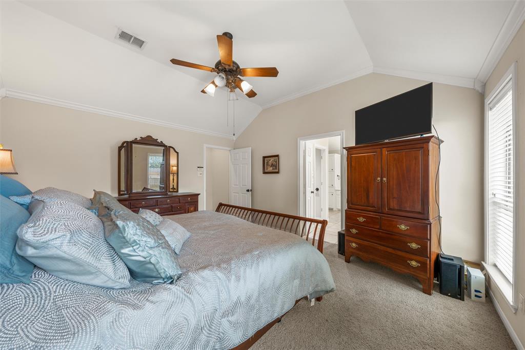 Vaulted ceiling bedroom featuring carpeting, crown molding, and a ceiling fan with integrated lighting