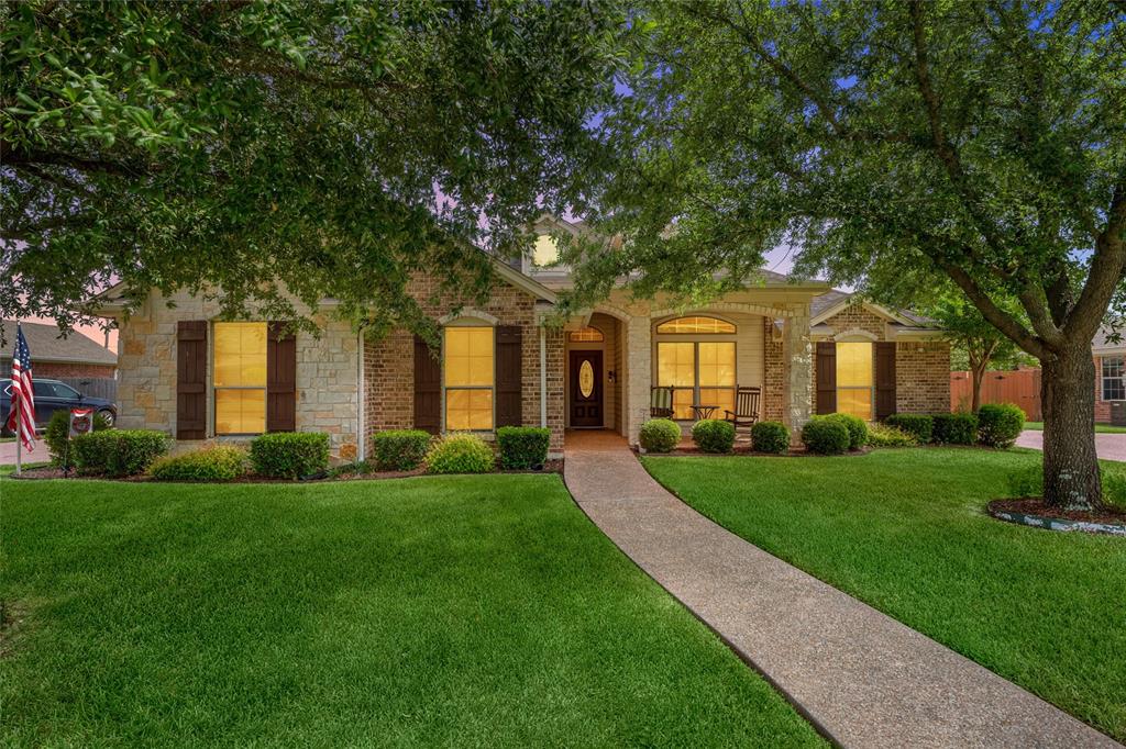 Stone and brick exterior featuring a covered entry, arched window, dark wood front door, and a concrete pathway Stone and brick exterior featuring a covered entry, arched window, dark wood front door, and a concrete pathway