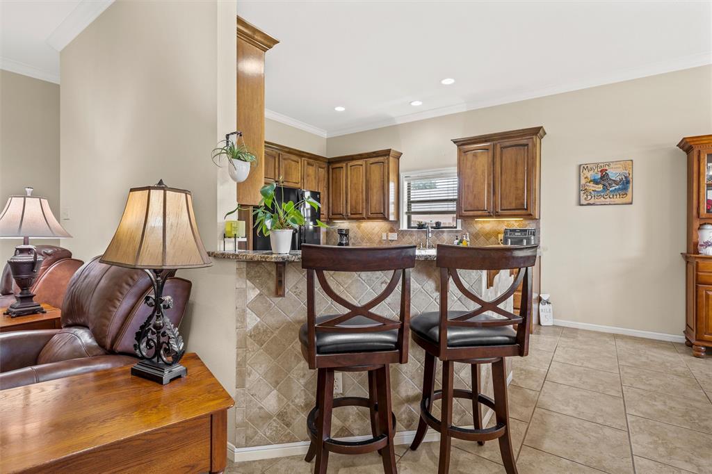 Kitchen bar area featuring a granite countertop, tiled backsplash, and recessed lighting