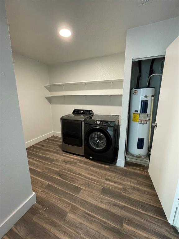 Laundry room with washing machine and clothes dryer, water heater, and dark wood-type flooring