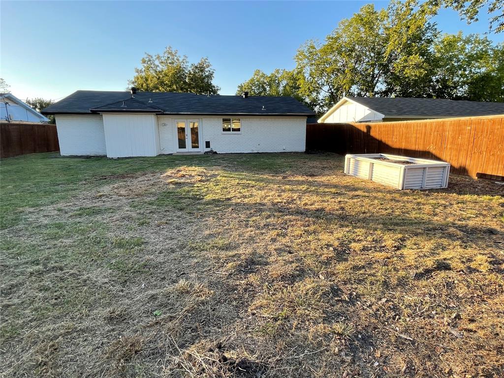 Rear view of house featuring a lawn and french doors