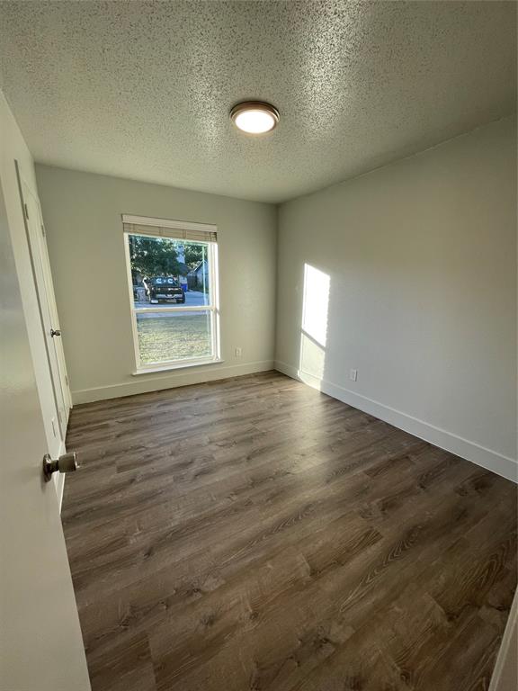 Spare room featuring a textured ceiling and dark hardwood / wood-style flooring