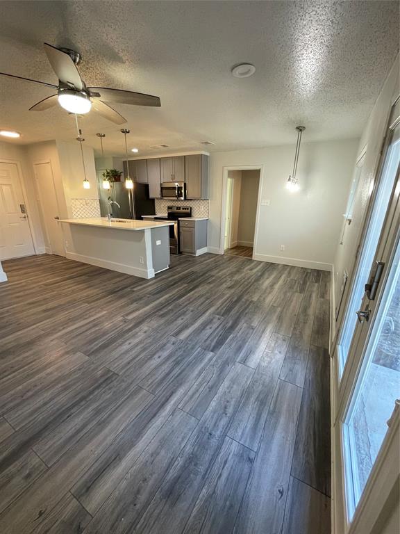 Kitchen with pendant lighting, stove, dark wood-type flooring, and a textured ceiling