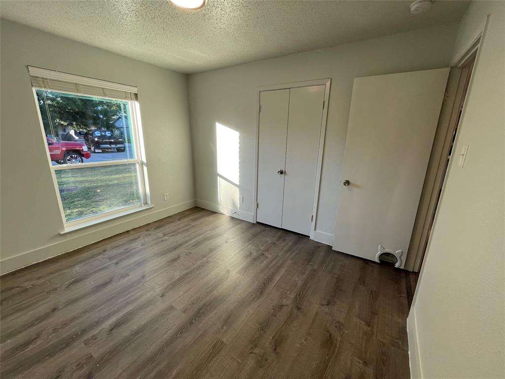 Unfurnished bedroom with a textured ceiling, hardwood / wood-style floors, and a closet
