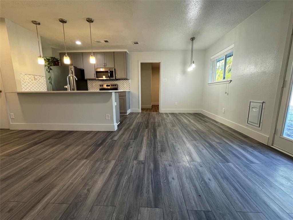 Unfurnished living room with a textured ceiling and dark wood-type flooring