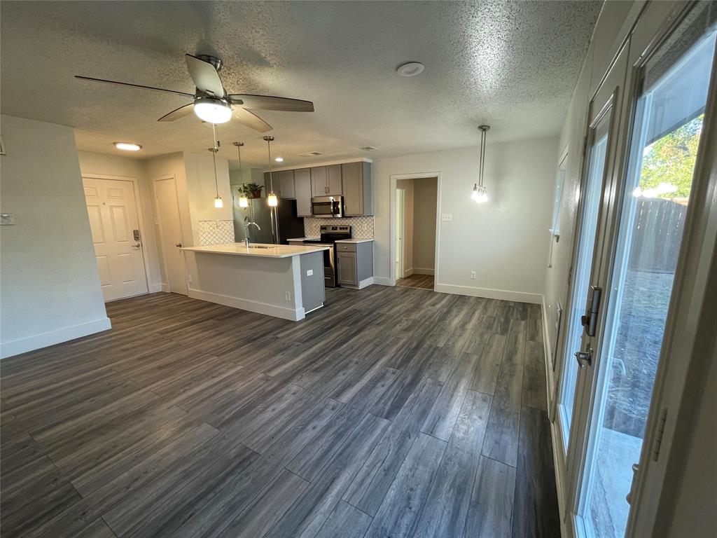 Kitchen with appliances with stainless steel finishes, hanging light fixtures, decorative backsplash, and dark wood-type flooring