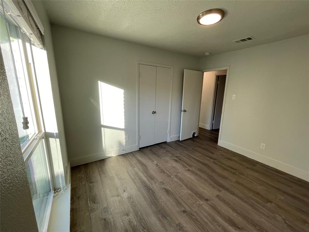 Unfurnished bedroom with hardwood / wood-style flooring, a closet, and a textured ceiling