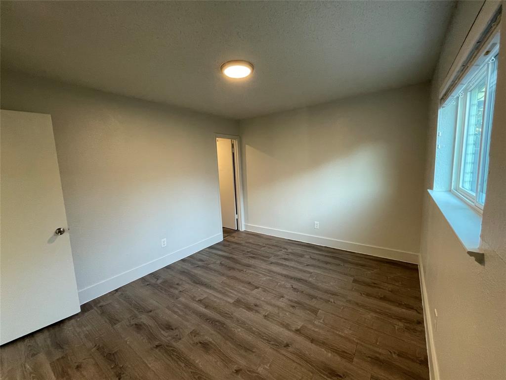 Unfurnished room with a textured ceiling and dark hardwood / wood-style flooring