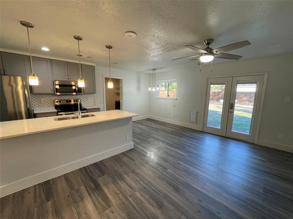 Kitchen with dark hardwood / wood-style floors, pendant lighting, stainless steel appliances, and ceiling fan