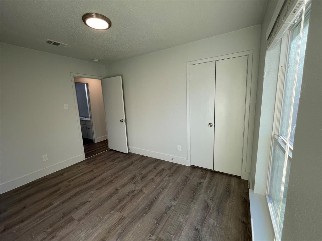 Unfurnished bedroom featuring a textured ceiling, dark wood-type flooring, and a closet