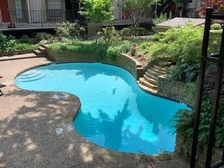 Freeform swimming pool with integrated steps, surrounded by a stone-edged planter and concrete decking Freeform swimming pool with integrated steps, surrounded by a stone-edged planter and concrete decking