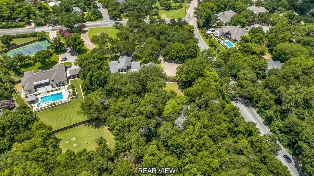 Expansive, tree-lined property featuring a large residence with a private swimming pool, surrounding patio, and a vast lawn area