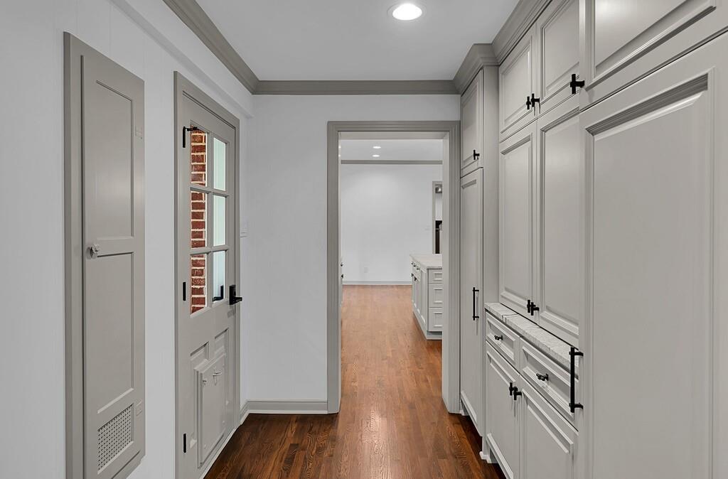 Hardwood flooring throughout, showcasing extensive built-in cabinetry with black hardware, recessed lighting, and a paneled door with glass inserts