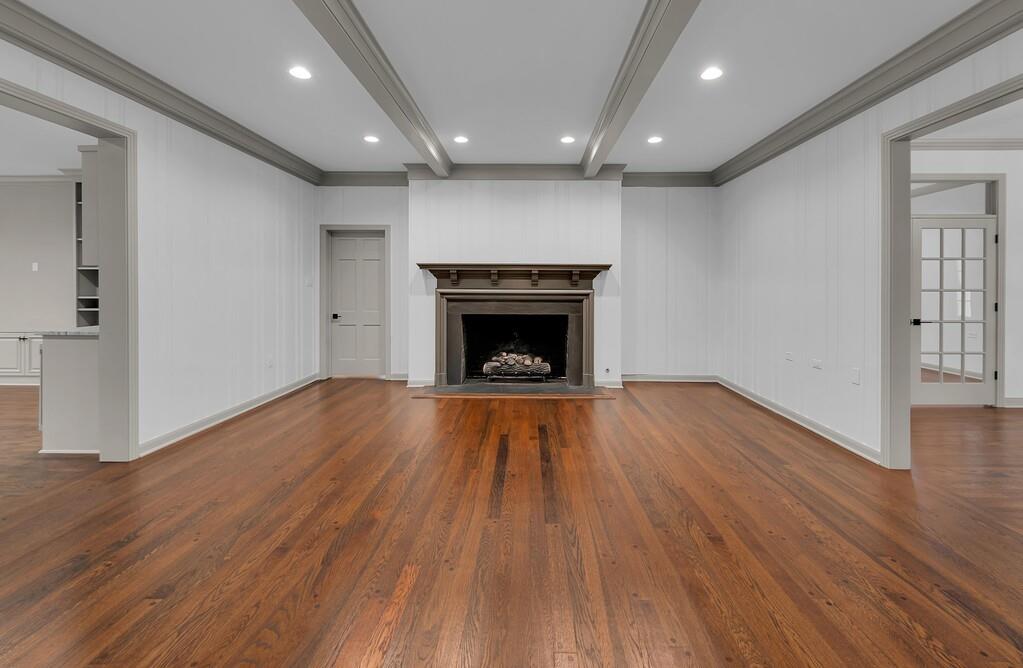 Spacious interior featuring wood-finish flooring, a central fireplace with an ornate mantel, recessed lighting, and crown molding
