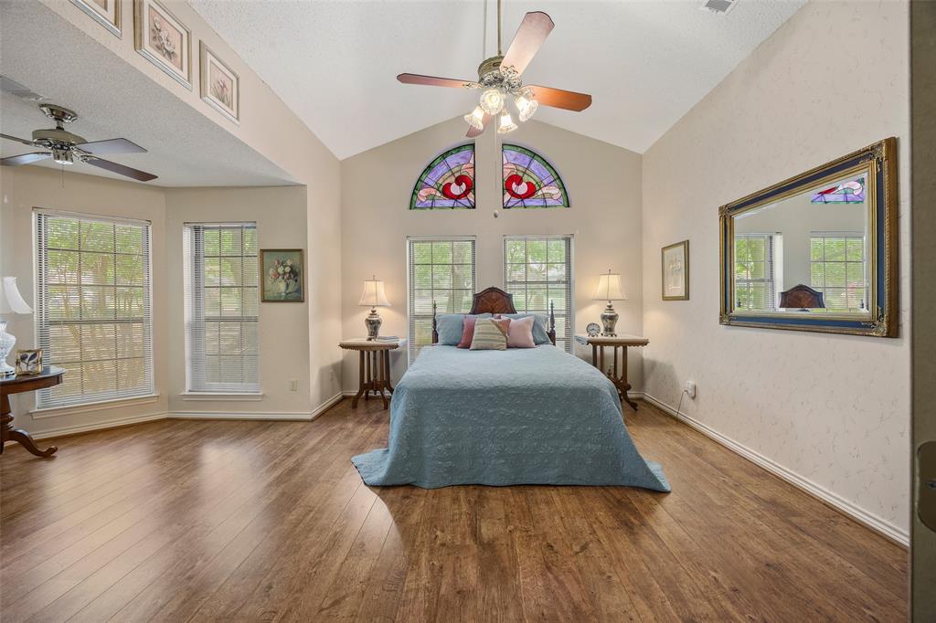 Vaulted ceiling room featuring wood-finish flooring, multiple windows, and decorative stained-glass arch windows